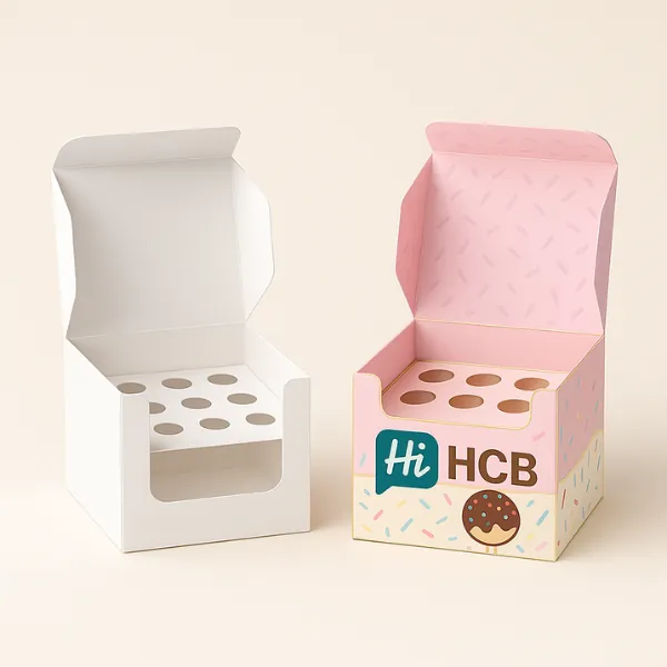 Two cube cake pop boxes with round windows - one plain- one pink with HCB logo and confetti inside- class=