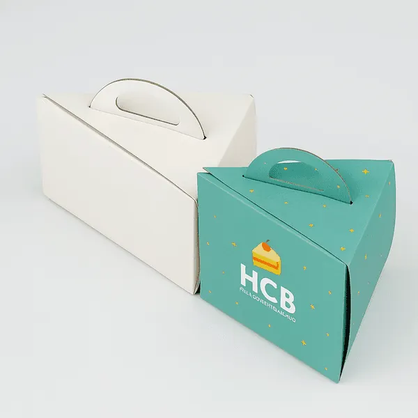 Two triangle cake slice boxes one plain white one printed with HCB logo and starry green design