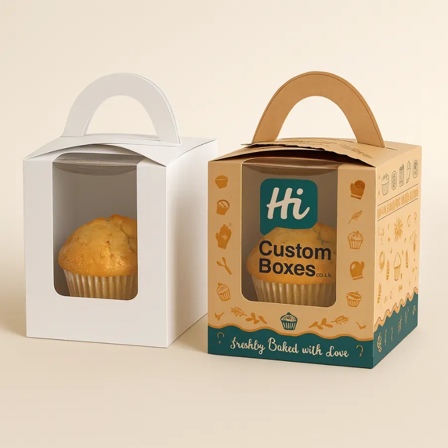 Two single muffin packaging boxes with handles and a clear window- one in white and one in custom-printed kraft paper- holding a single baked muffin class=