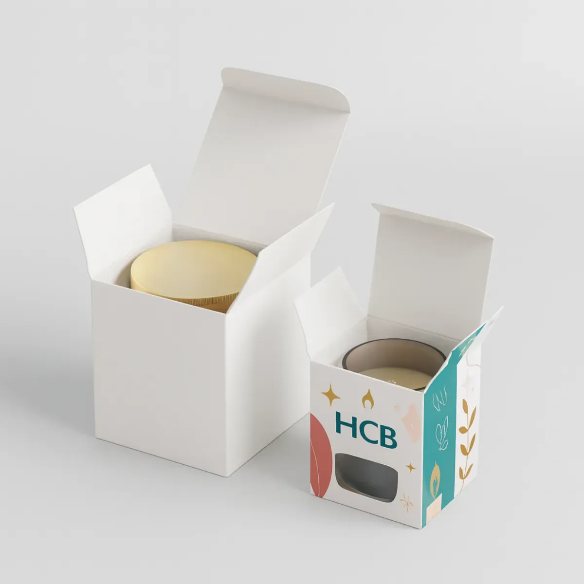 Open tuck end candle packaging box mockup- one plain white and one printed with HCB logo- gold stars- and floral graphics- holding a candle with a golden lid class=