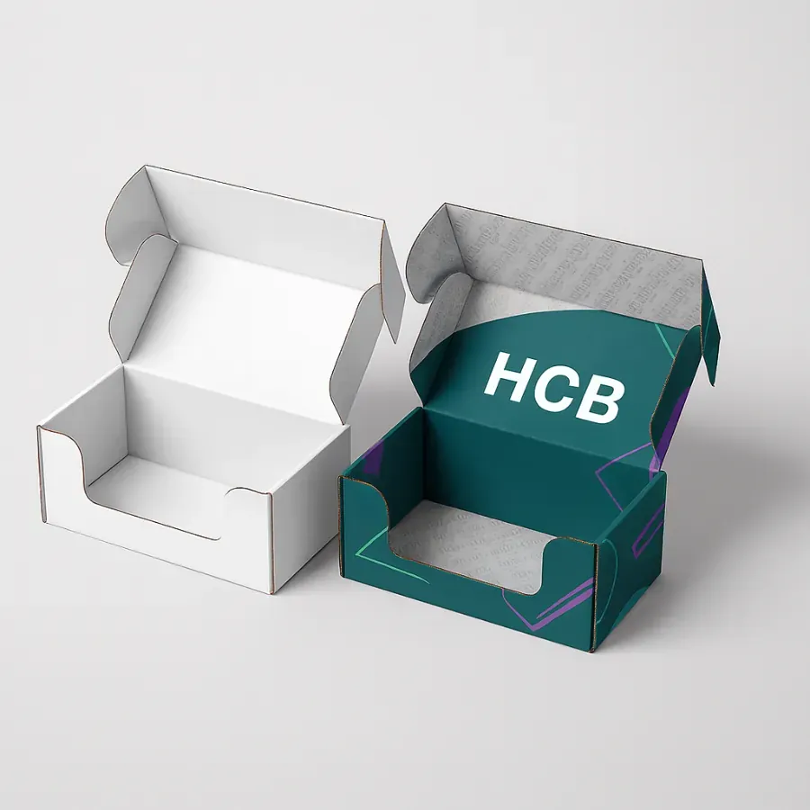 Two open mailer boxes with a front cutout to display contents- One is plain white- and the other is custom-printed in teal and purple with an -HCB- logo class=