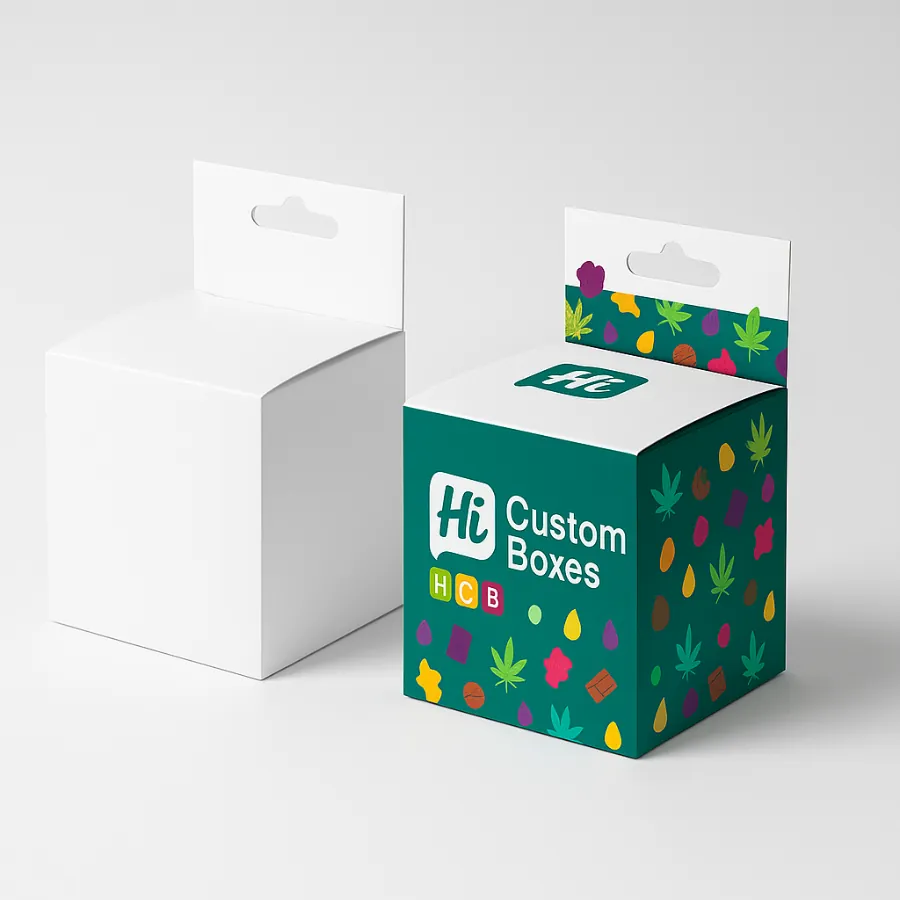 Two small cube boxes for edibles packaging with a hang tab- one plain white and one in a colorful leaf and candy pattern on a teal background- class=