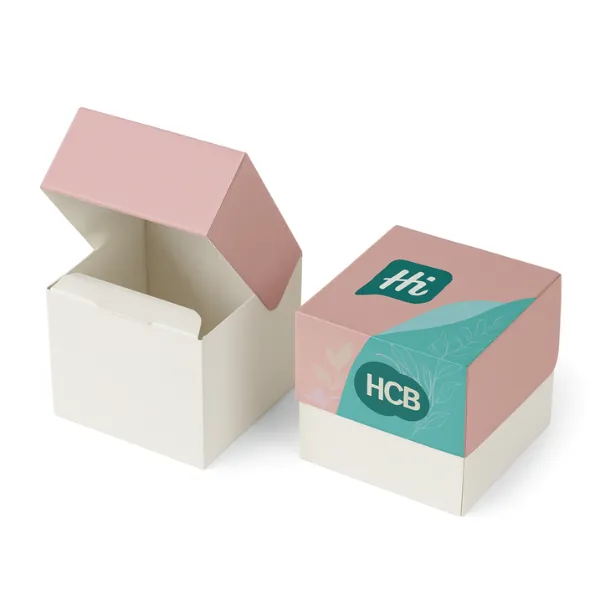 Square flip-top box mockup with plain white style on the left and branded version on the right with pink lid- teal side panels- floral graphics- and -Hi HCB- logo- class=