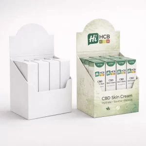 A retail counter display unit containing several small white cardboard boxes for CBD skin cream.