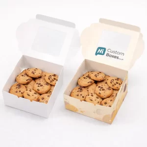 Two open square biscuit boxes with windowed lids, filled with various chocolate chip cookies.