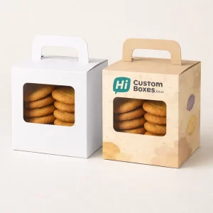 Two square biscuit boxes with carry handles and rectangular windows showing golden cookies inside.