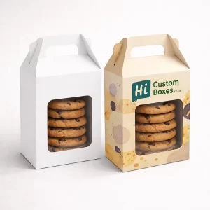 Two tall cardboard boxes with handles and clear windows, filled with stacked chocolate chip cookies.