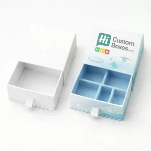 Drawer-style slide boxes, one plain white and one with a light blue eye-themed design and internal dividers.