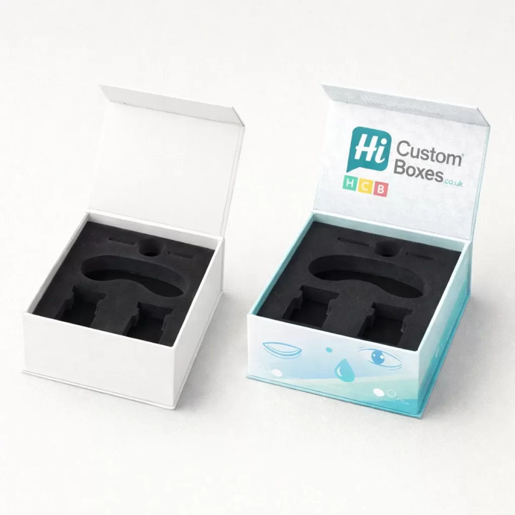Two flip-top rigid boxes with black foam inserts, one plain white and one featuring light blue branding.