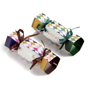 Two decorative harlequin pattern gift crackers tied with green and brown ribbons on white.