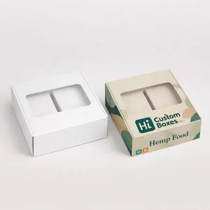 Two square boxes with clear viewing windows, including a printed version with green leaf designs and branding.