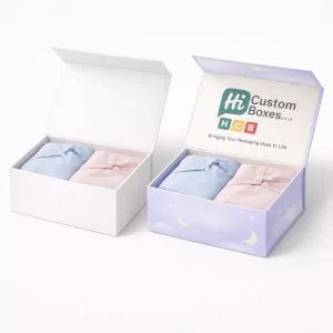 Two premium magnetic gift boxes containing folded blue and pink sleepwear garments side by side.