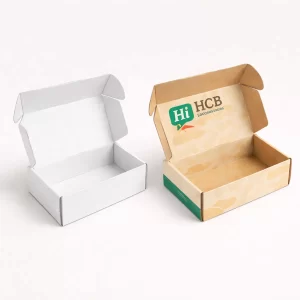 An open white corrugated mailer box next to a printed kraft shipping box with internal branding.