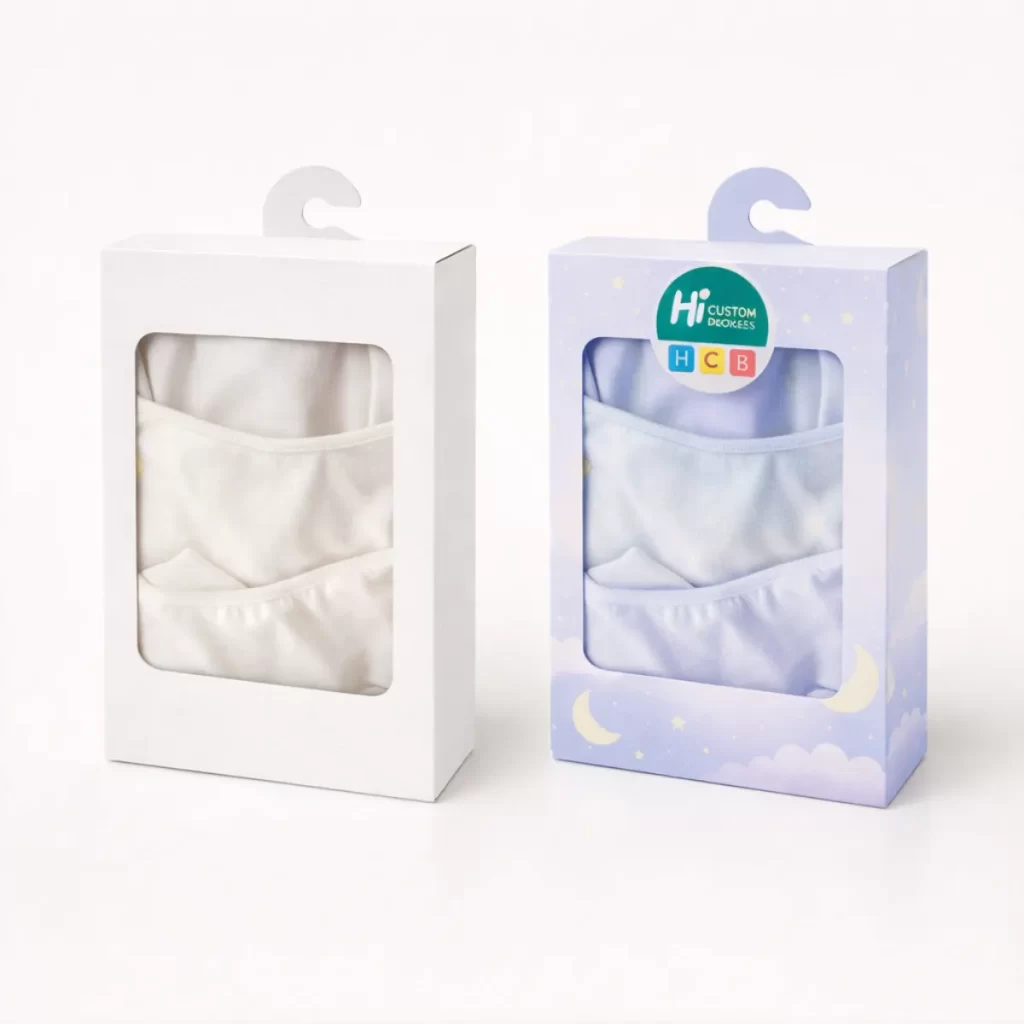 Two hanging retail boxes with windows showing folded white and light blue pyjama sets inside.