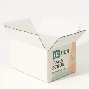 An open white corrugated shipping carton featuring printed face scrub branding on the front panel.