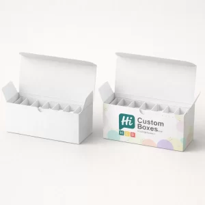 Two elongated white ballotin boxes with dividers, one decorated with a branded pastel circle pattern.