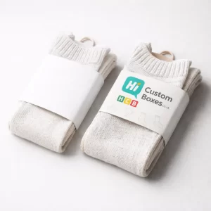 Two pairs of cream-coloured woollen socks held together by branded white paper belly band wraps.