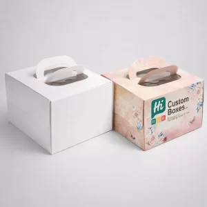 Square white and floral patterned bakery boxes with top windows and sturdy curved carrying handles.