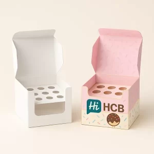 Two cube cake pop boxes with round windows - one plain- one pink with HCB logo and confetti inside