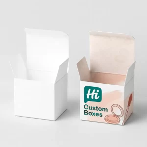 Two tuck-top cosmetic boxes. The left one is plain white, and the right one is printed with "Hi Custom Boxes" branding in teal and peach shades, featuring cosmetic icons inside and outside.