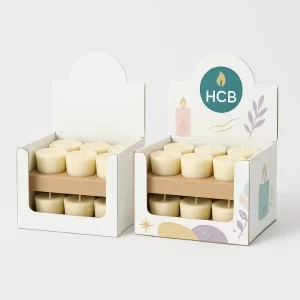 Counter display boxes filled with tealight candles, one plain white and one decorated with colorful illustrations of candles, leaves, and the HCB logo on the header.