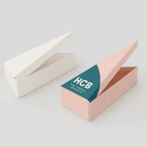 Two wedge shaped cake slice boxes one plain white one pink with HCB branding and stylish graphics