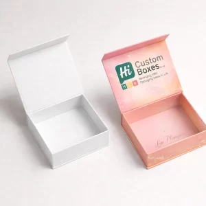 Two open square gift boxes with magnetic lids, featuring a white interior and pink branded design.