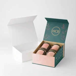 Plain white rigid box beside an open luxury rigid box with pink and teal design- gold -HCB- branding inside- and floral illustrations