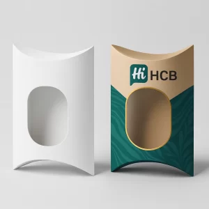 White pillow box with an oval die-cut next to a kraft paper box with green design and a clear window