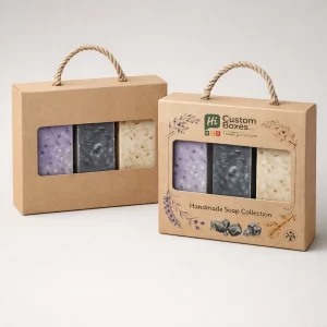Two large kraft paper gift boxes with rope handles and a rectangular window displaying three different soap bars.