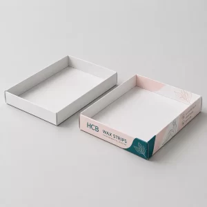 A plain white display tray standing next to a pink floral branded tray for wax strips.