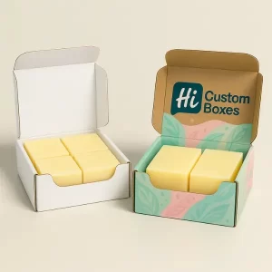 Two mailer-style soap boxes- one plain white and one custom printed with pastel leaf patterns- each holding four yellow soap bars inside