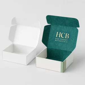 White and green branded postal-style boxes with gold foil -HCB- logo for botanicals