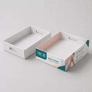 Two cardboard display trays with upright back panels, featuring elegant pink floral designs and logos.